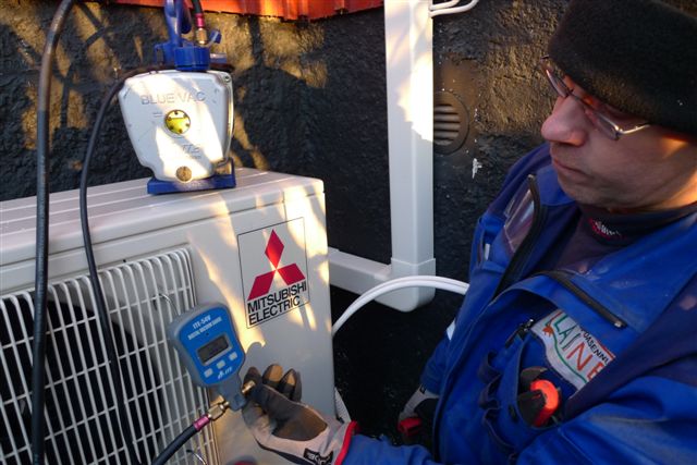 Pekka Laine asentaa ilmalämpöpumpun ulkoyksikköä.